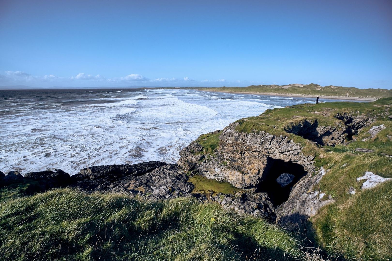 Wind-swept rocky Cornish coast with foaming waves and grassy cliffs